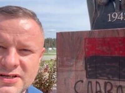 Zdewastowany pomnik ofiar ludobójstwa na Wołyniu. Czerwono-czarna flaga i napis