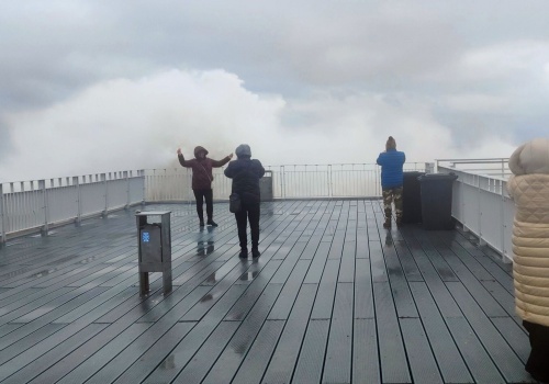 Wiatr, wzburzone morze i zadowoleni turyści z aparatami