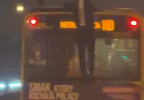 Młody mężczyzna trzymał się tyłu jadącego autobusu, następnie wspiął się i chodził po dachu